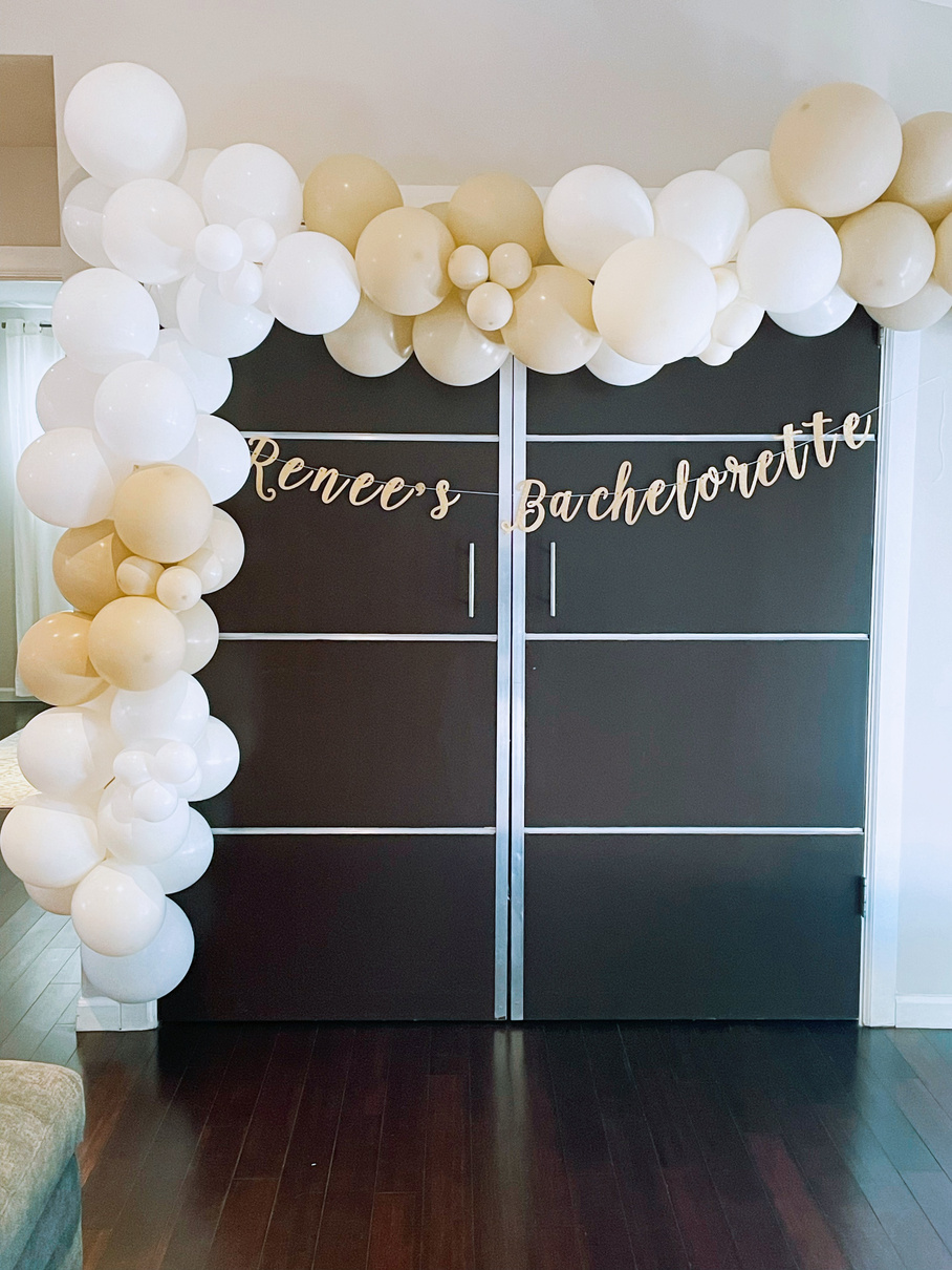 a black and white photo of a balloon arch with white and gold balloons